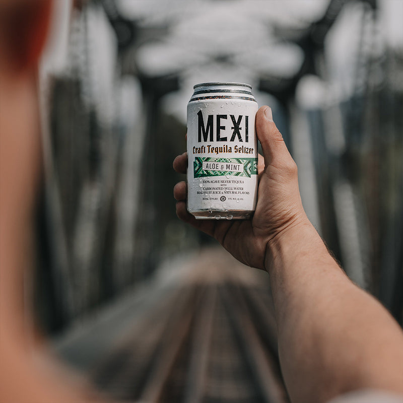 Holding a Can of Aloe Mint Mexi Seltzer by a Bridge
