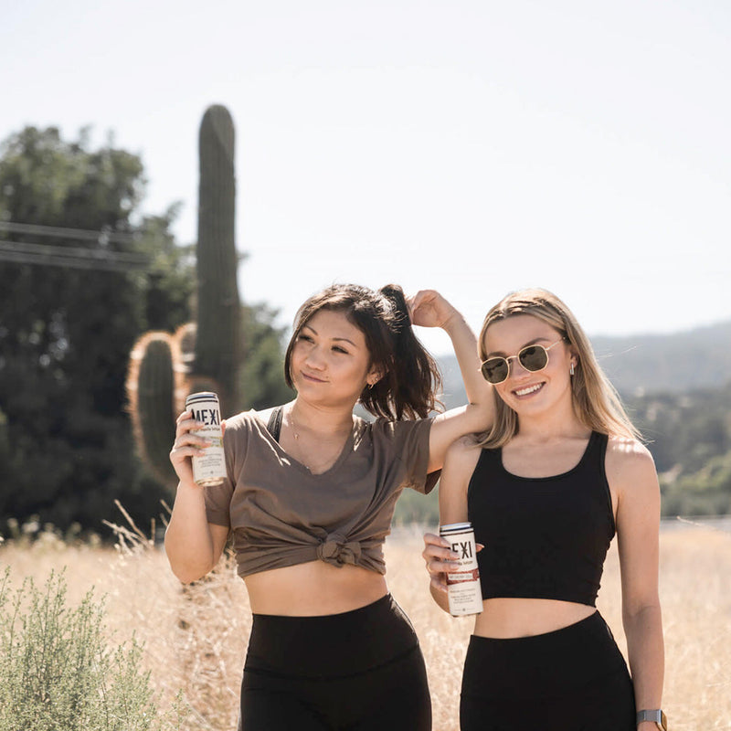 Two ladies holding cans of Prickly Pear Iced Tea Mexi Seltzer